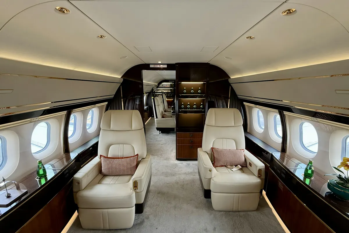 Looking down the aisle of a large private jet cabin with cream leather seats