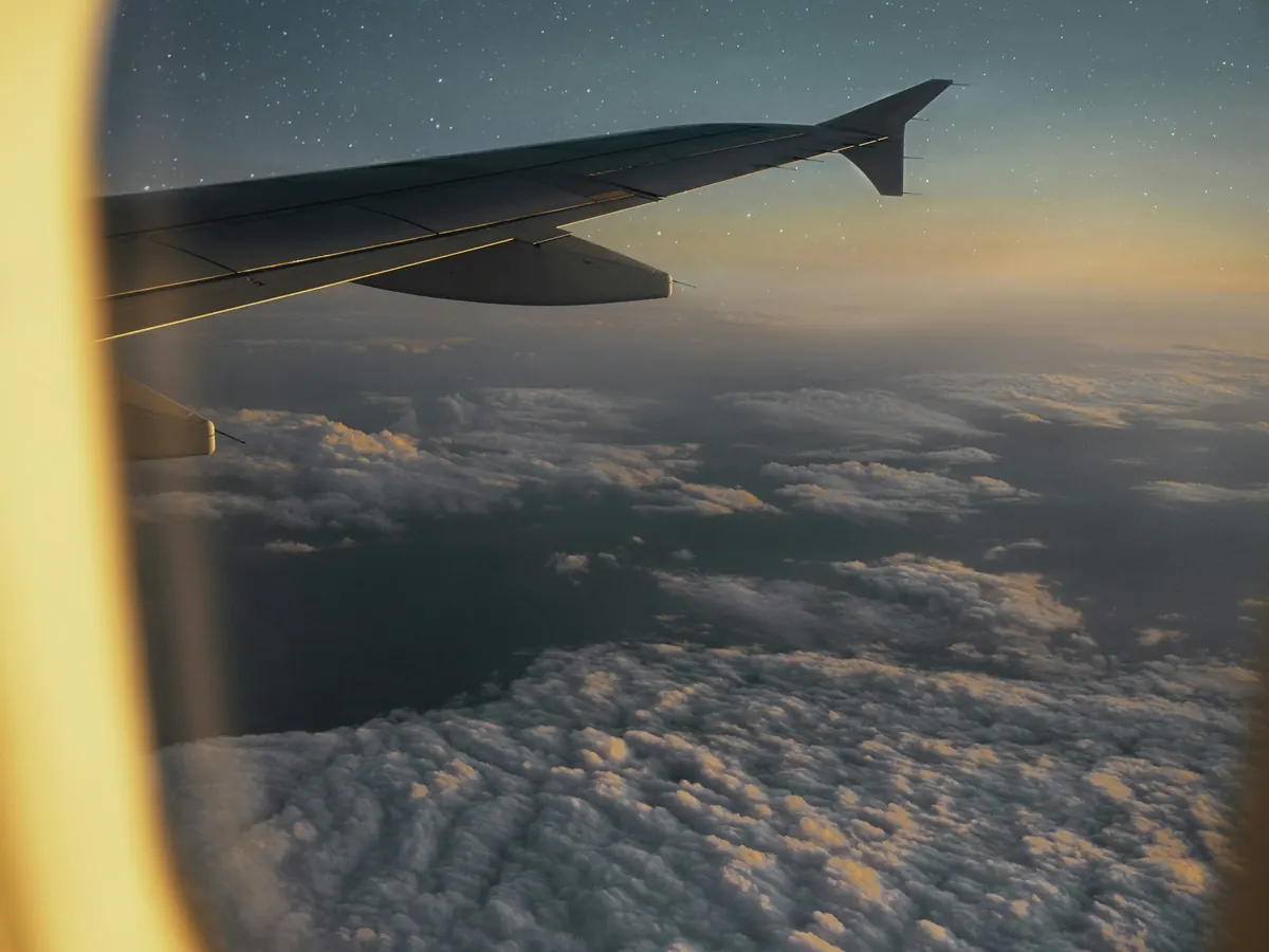Aircraft wing and evening clouds seen through a cabin window