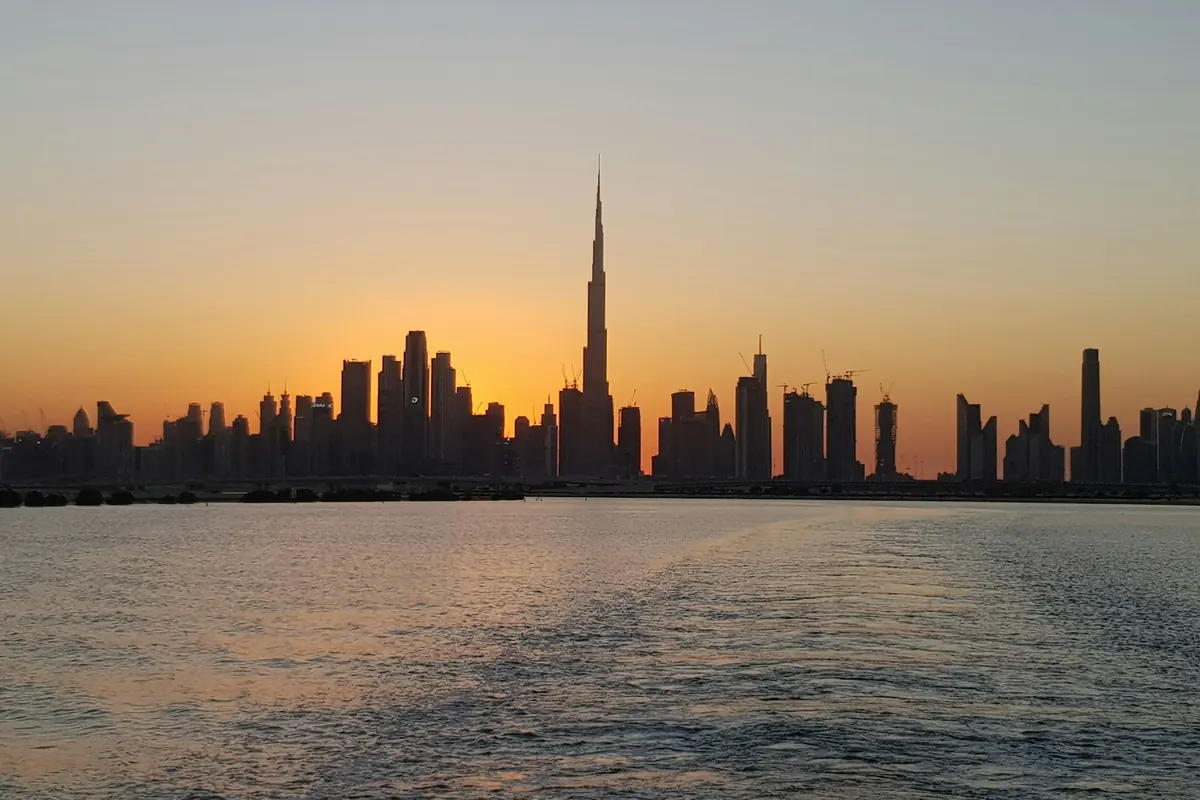 City skyline silhouetted against an orange sunset over the water