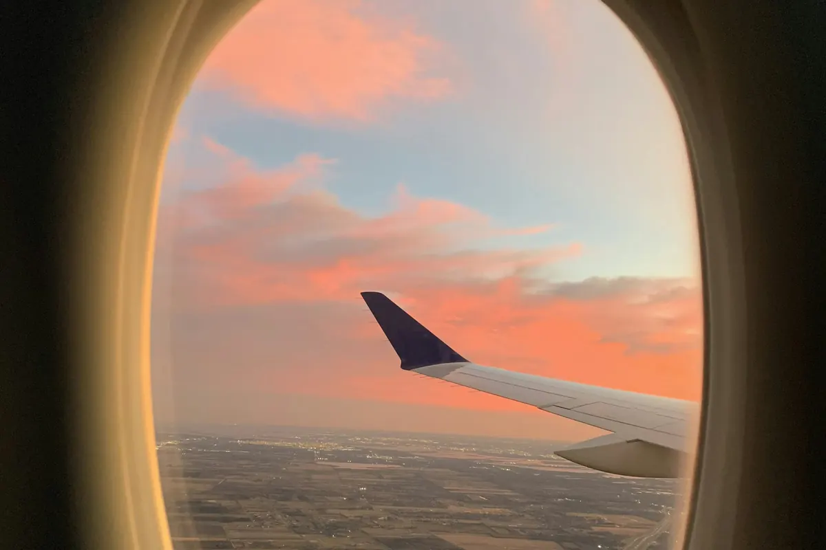 Pink and blue evening sky and a wingtip framed by an aircraft window